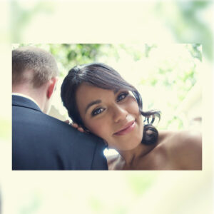 bride with soft makeup posing on groom's shoulder