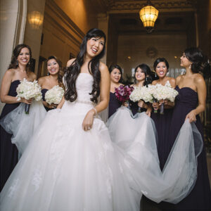 asian bride with bridal party holding dress